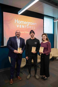 Homegrown Ventures conference with speakers Gus Minor, Dylan Lloyd, and Hilary Deverell holding plaques