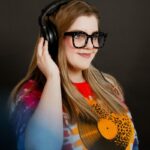 meagan brownrigg from grove betty wearing headphones and thick framed glasses